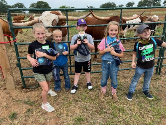 Each child gets a Bible at Gospel Rocks Ranch. In this photo, you see the kids holding the Bibles and bandanas they got at Gospel Rocks Ranch. The child in the middle is holding a gnome which was part of the scavenger hunt. Courtesy of Jon Hager