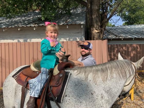 Addilyn Easlon riding Rooster led by her dad, David Easlon. Holding award for Best Dressed Cowgirl in the parade. Courtesy of Kayla Easlon