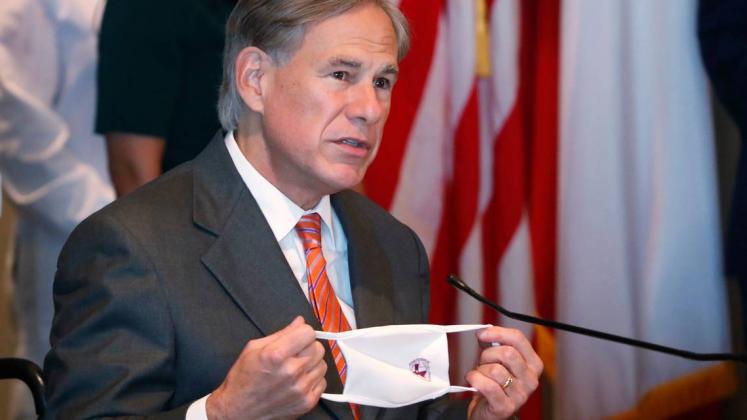 Texas Gov. Greg Abbott holds up mask as he talks about the importance of wearing face coverings to prevent the spread of COVID-19 during a news conference in Dallas, Thursday, Aug. 6, 2020. LM OTERO AP