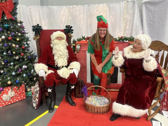 Santa, a Jolly Elf, and Mrs. Claus waiting for the arrival of our SSES students and families!