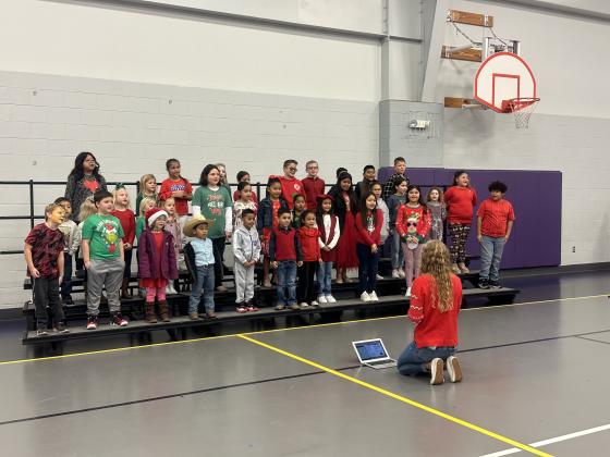 Jessica Fuller, SSES Music Teacher, leading a small group of SSES students grades PK-4 singing Christmas songs.