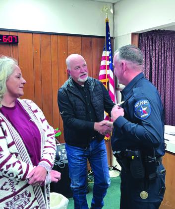 City Manager Scott Edmonson shaking hands congratulating Chief Newkirk as Newkirk's wife proudly watches