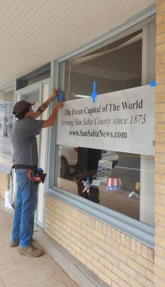 Devin Cordoza is seen here installing the Perforated Vinyl sign on our front window this week. Photo by Carolyn Boswell-Preece