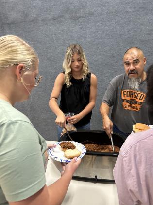 Robert and Mae are serving dinner to the group.