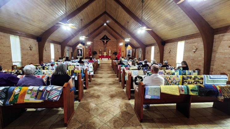 Fr. Joe blesses the quilts, some of the recipients, and volunteers at St Mary’s Catholic Church.