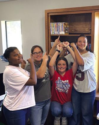 Pictured right: Lisa, Susan, Theresa, and McKenna showing off their planning and carpentry skills with their DVD shelf in the library. Looks good, girls!
