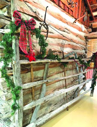 The tool-laden gate in the dog trot of the log cabin still has room for Christmas decorations. Photo by Aileen Roberts