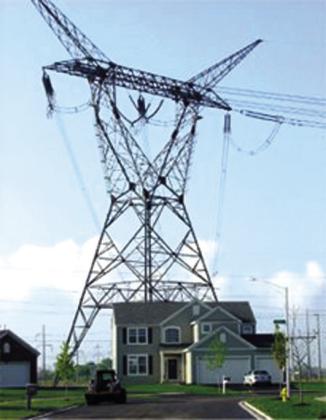 A photo showing a 140-foot tower for a 765kV transmission line next to a two story house. Courtesy of Dave Clark