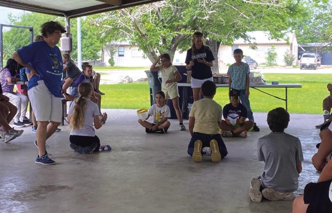 These students are participating in the Basket activity. The basket activity is making a game from repurposed trash. Papers are wadded into balls; the basket is a cut plastic gallon. The students, team up and work together to race their opponents in a race to get more baskets made then the opposing team.