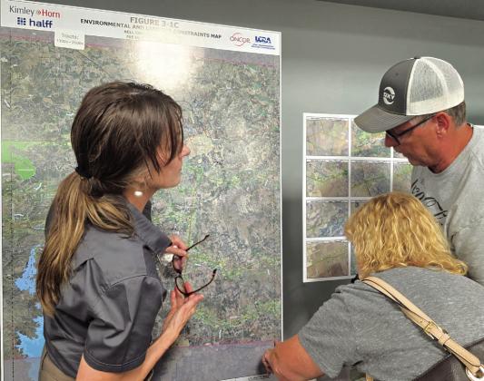 Kelly Wells with the Lower Colorado River Authority shows two landowners where their property is situated on one of the large maps that depicted the proposed routes. Photo by Emily Hilley-Sierzchula/News