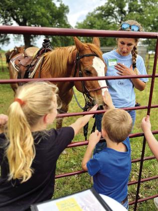 Here is a volunteer showing two kids how to pet and be gentle with a horse at Gospel Rocks Ranch. Courtesy of Jon Hager