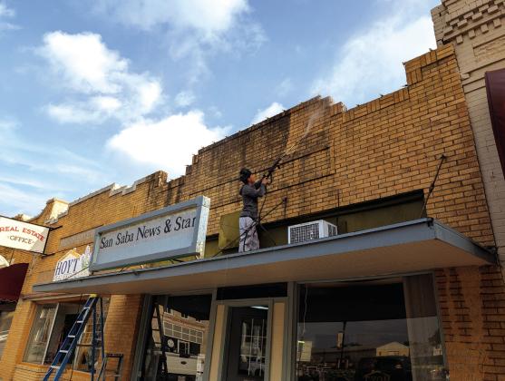 Angel, employee of Home X Custom Construction/Renovation, pressure-washes years of dust and grime from San Saba News &amp;amp; Star’s front entry giving the historic facade a fresh look. News Staff photo