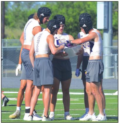San Saba High School varsity football senior quarterback Lance Taylor (center) and his teammates huddle together to discuss an offensive play on Monday, June 20th, during the Dillos’ 7-on- 7 summer scrimmage vs. Mason High School held at Jacket Stadium in Llano. (Photo by Andrew Salmi)
