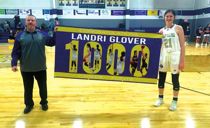 Pictured at left: San Saba High School girls varsity basketball senior forward Landri Glover (21) happily holds up a banner with Lady Dillos head coach Chris Jost after Glover scored her 1,000th career point over a four-year span playing basketball for the Lady Dillos. (Photo courtesy of San Saba All-Sports Booster Club)