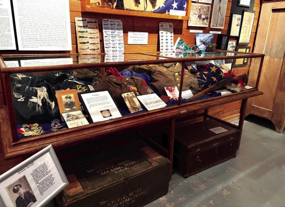 This cabinet at the museum honors the service of George Jennings (Korea), Benton Miller, Fayette Moore, and Newell Oliver. There is also a 48-star United States flag. The sign in front of the cabinet honors Felix E. Scott.