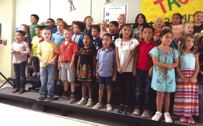 Kindergarten and 1st grade students performing their song
