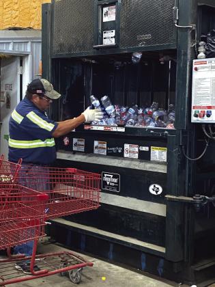 Alonzo Jimenez putting plastic bottles into the compactor for bundling and recycling