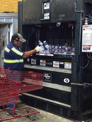 Alonzo Jimenez putting plastic bottles into the compactor for bundling and recycling