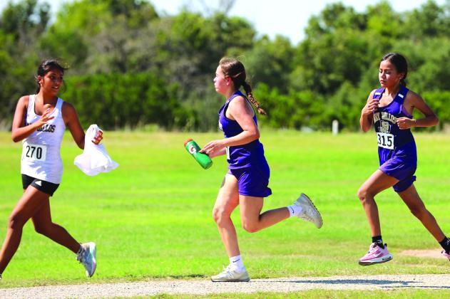 Leslie Yanez passing water off and cheering on 7th grade runners Lizbeth Perez and Sophia Hernandez in during their race in Goldthwaite.