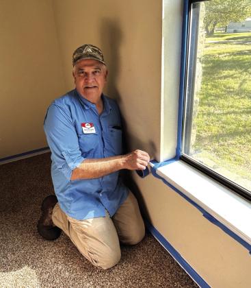 Marlon is taping off the windows to prepare for painting. Courtesy of Janice Hull