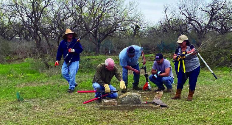Examining a newly cleared Harkeyville cemetery gravesite are Jerry Blankenship, Dario Jimenez, Miguel Flores, and Sarah Saldivar. Sambo Martinez is to the left of the group. Photo by Lynn Blankenship