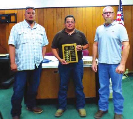 Alonzo Jimenez, Sanitation Department Employee, displays an Employee of the Month plaque with his name engraved for selection as the City's Employee of the Month for September. He also received a gift certificate to a local restaurant. On Alonzo’s right is Juan Montoya, Sanitation Department Supervisor, and to his left is Michael Nelson, Alderman.