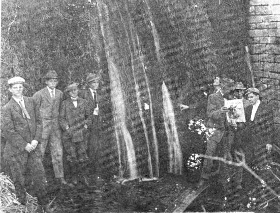 MILL POND FALLS––and how it looked on May 2, 1911. Our thanks to Mrs. Otto (Naomi) Harkey for the picture of the past. On the back of the Postcard were the names in order: Rex Drew, Willie White, Wiley Murray, Reeves Kykendall, Worth Dockray, George Gaddy, Shelton Braly and William Hoyt. The boys to the right are interested in a magazine with the name "The American Boy." Note also the doublebreasted suit, knickers and variety of hat styles.