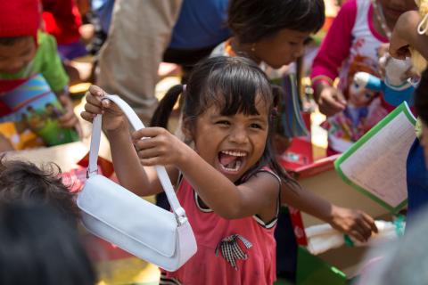 At a morning outreach event in a village in Cambodia, a girl rejoices at the purse she found inside her shoebox gift.