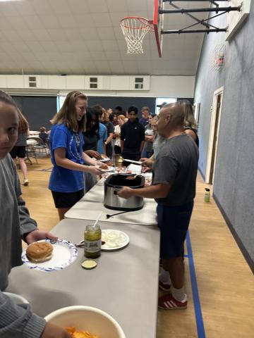 Robert and Mae are serving dinner to the group.