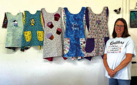 Toni Hill worked on her new embroidery machine and taught everyone how to make these beautiful reversible aprons. Photo by Debbie Phelan