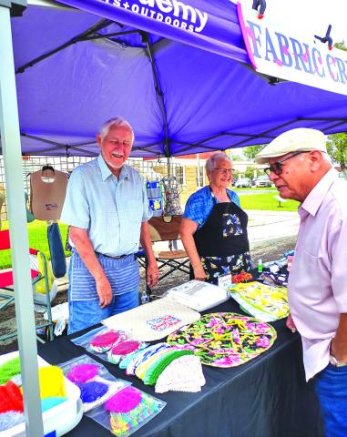 Don and Joan Van Gorp are showing their items to a perspective customer. Among their items were: aprons, baby buntings, oven towels, scrubbies, knitted washcloths, neck pillows, bibs for adults and children, and hair turbans. Everything at their booth is homemade. - Staff Photo