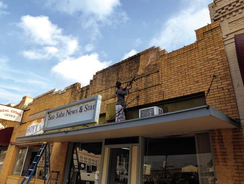 Angel, employee of Home X Custom Construction/Renovation, pressure-washes years of dust and grime from San Saba News &amp; Star’s front entry giving the historic facade a fresh look. News Staff photo