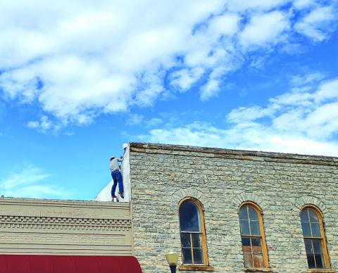 Jake Uptain is climbing up the next level of roof while he grabs the hand of G. T. Meador and Kyle Anderson gives him a boost.