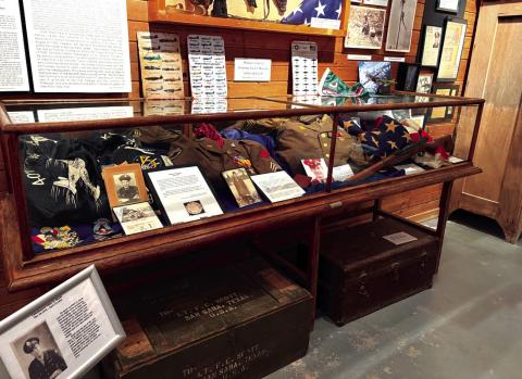 This cabinet at the museum honors the service of George Jennings (Korea), Benton Miller, Fayette Moore, and Newell Oliver. There is also a 48-star United States flag. The sign in front of the cabinet honors Felix E. Scott.
