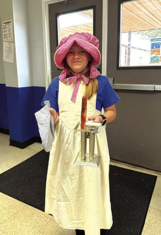 Preslee Duggan from Cherokee ISD 7th grade Texas History class holds a candle making form, wearing the all important apron and sunbonnet from the Daughters of the Republic of Texas Traveling trunk.