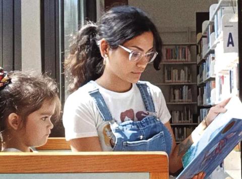 Amity, left, and Yvette Adams, granddaughter and daughter of Yvonne Contreras, enjoying a book at the library.