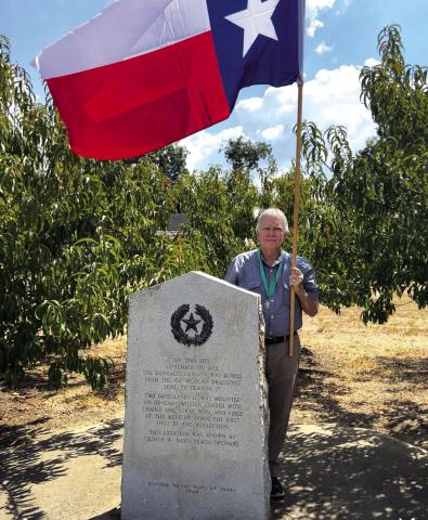 O. Scott Dunbar, KSJ is pictured here with the Commemorative Flag at the Gonzales Cannon Burial Site. Marker Inscription: On this site September 29, 1835 the Gonzales cannon was buried from the 150 Mexican Dragoons sent to demand it. Two days later it was mounted on ox-cart wheels, loaded with chains and scrap iron, and fired at the Mexican Army, the first shot of the Revolution. This location was known as George W. Davis Peach Orchard. O. Scott Dunbar, KSJ